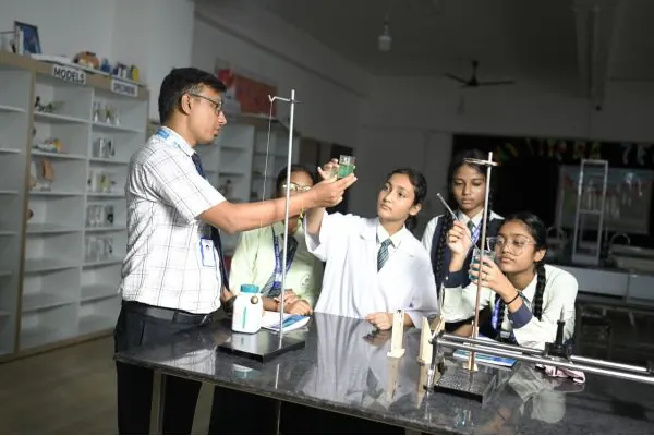 Teacher guiding students in the science laboratory of Mount Litera Zee School, Islampur
