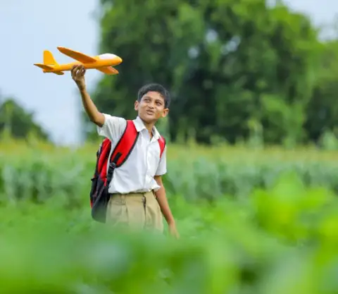 Boy with toy aeroplane in a green field